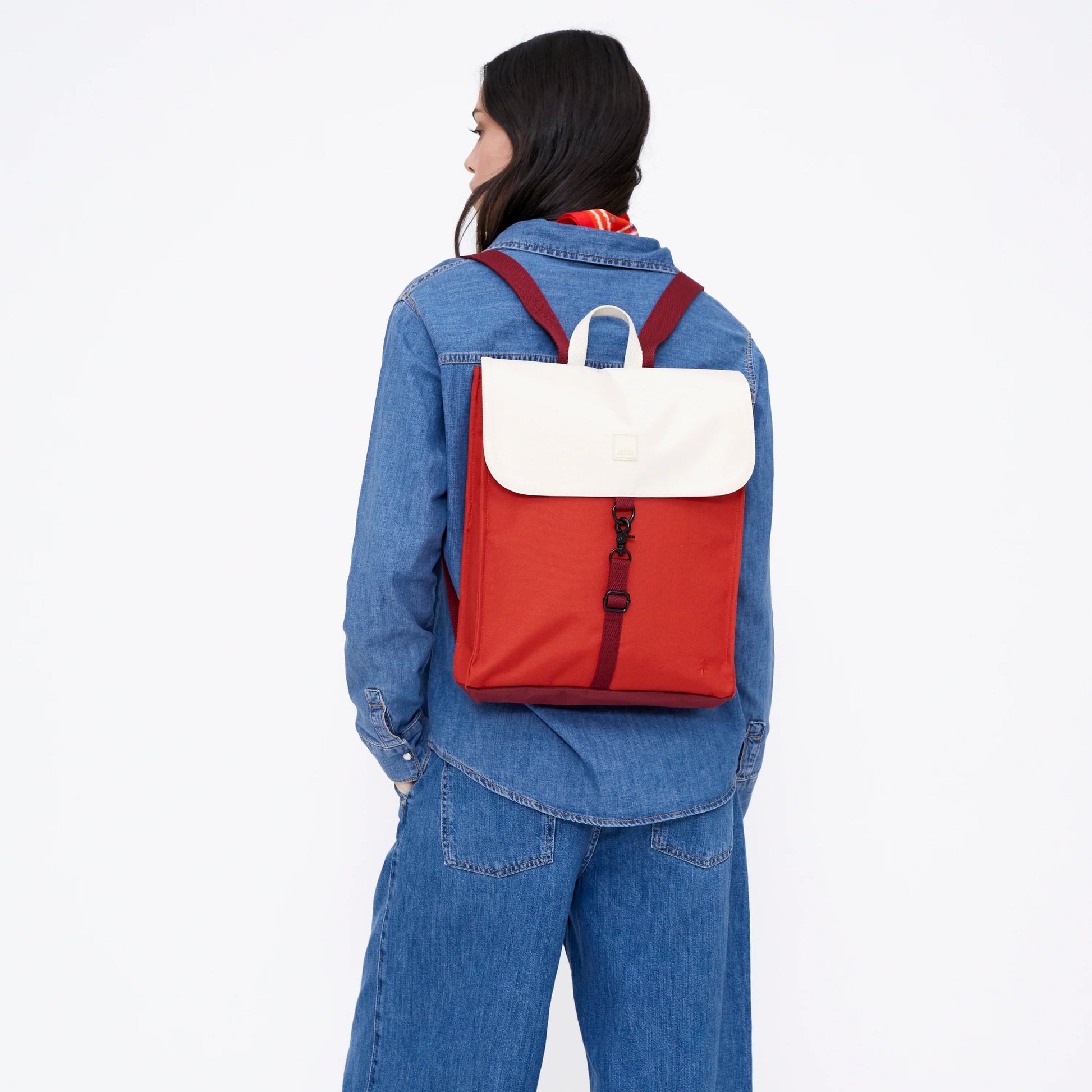 Mujer vestida de vaquero con una mochila reciclada e impermeable blanca y cereza de Lefrik