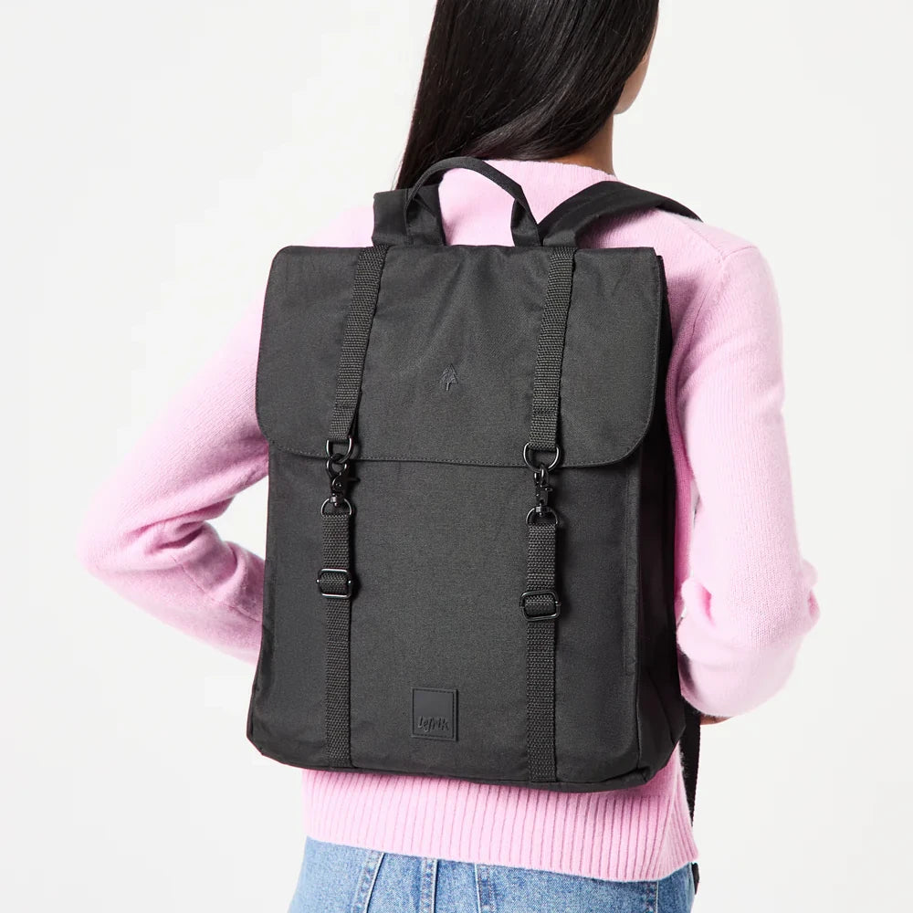 Mujer de espaldas con jersey rosa y la mochila plana negra reciclada e impermeable de Lefrik