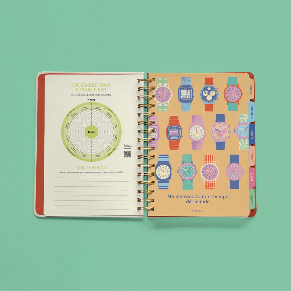 Interior abierto de la agenda Happimess 2027 mostrando la página de checkpoint mensual con rueda de áreas de vida y sección de logros a la izquierda, y el separador mensual ilustrado con relojes coloridos y la frase "Me merezco todo el tiempo del mundo" a la derecha, con pestañas de colores por mes