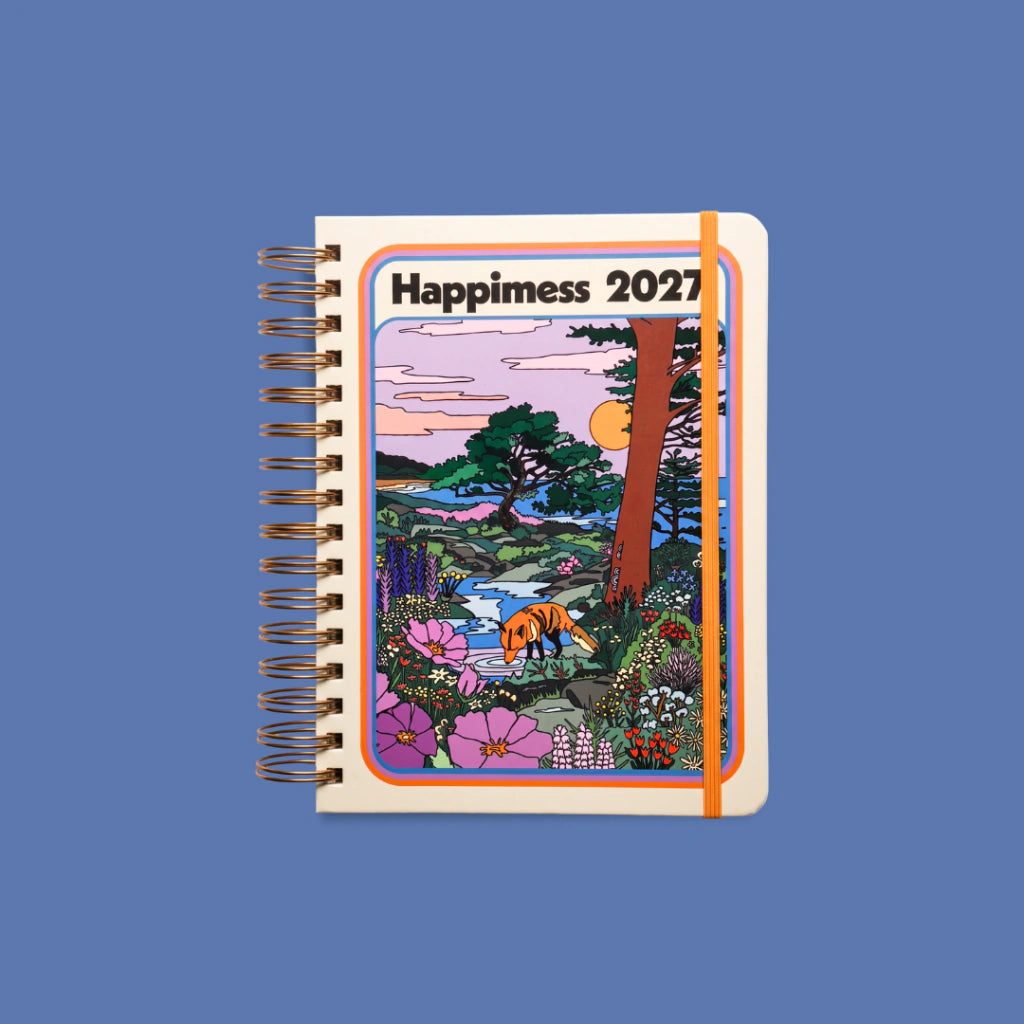 Agenda diaria 2027 Mis sueños me necesitan de Happimess con tapa dura ilustrada con un zorro en un paisaje natural de flores y árboles, encuadernación de anillas doradas y goma elástica naranja