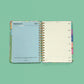 Interior agenda semanal 2027 Happimess Primavera abierta mostrando separador mensual azul de febrero con frase motivacional y página semanal horizontal con dias de lunes a domingo y pestañas de colores
