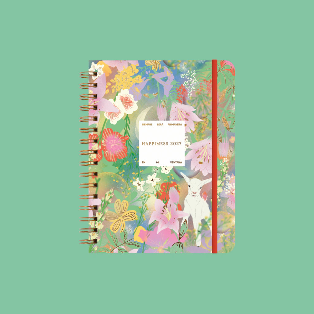 Agenda semanal 2027 Happimess Primavera cerrada con tapa floral ilustrada cabra blanca flores rosas rojas y amarillas espiral dorada y goma naranja fondo verde menta