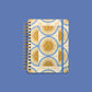 Agenda diaria 2027 Sol de mayo Happimess vista frontal cerrada con goma elastica azul, diseno de soles dorados sobre fondo azul