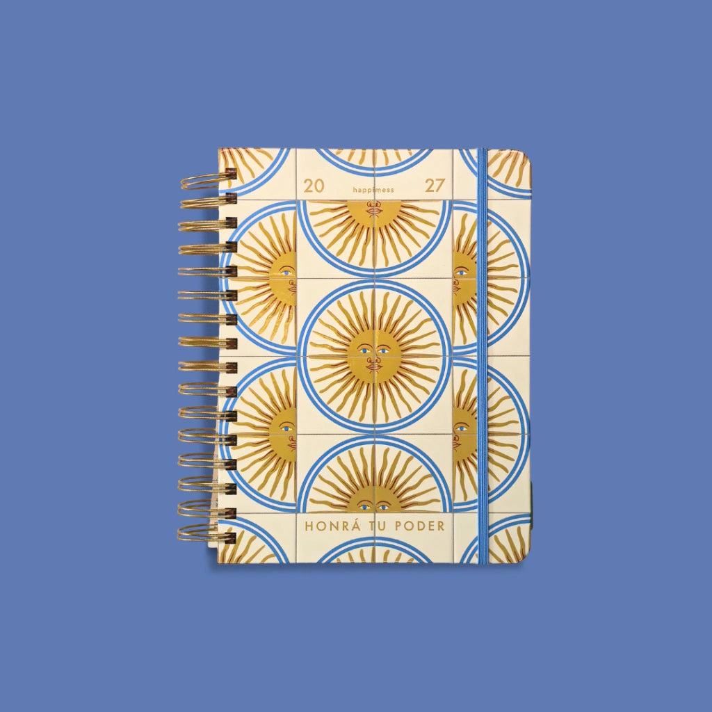 Agenda diaria 2027 Sol de mayo Happimess vista frontal cerrada con goma elastica azul, diseno de soles dorados sobre fondo azul