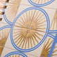 Agenda diaria 2027 Sol de mayo Happimess detalle de tapa con estampado de soles dorados con rostro y circulos azules