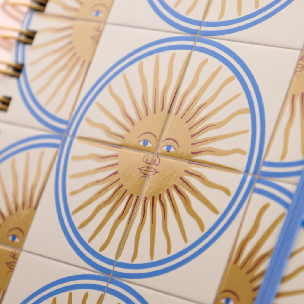 Agenda diaria 2027 Sol de mayo Happimess detalle de tapa con estampado de soles dorados con rostro y circulos azules