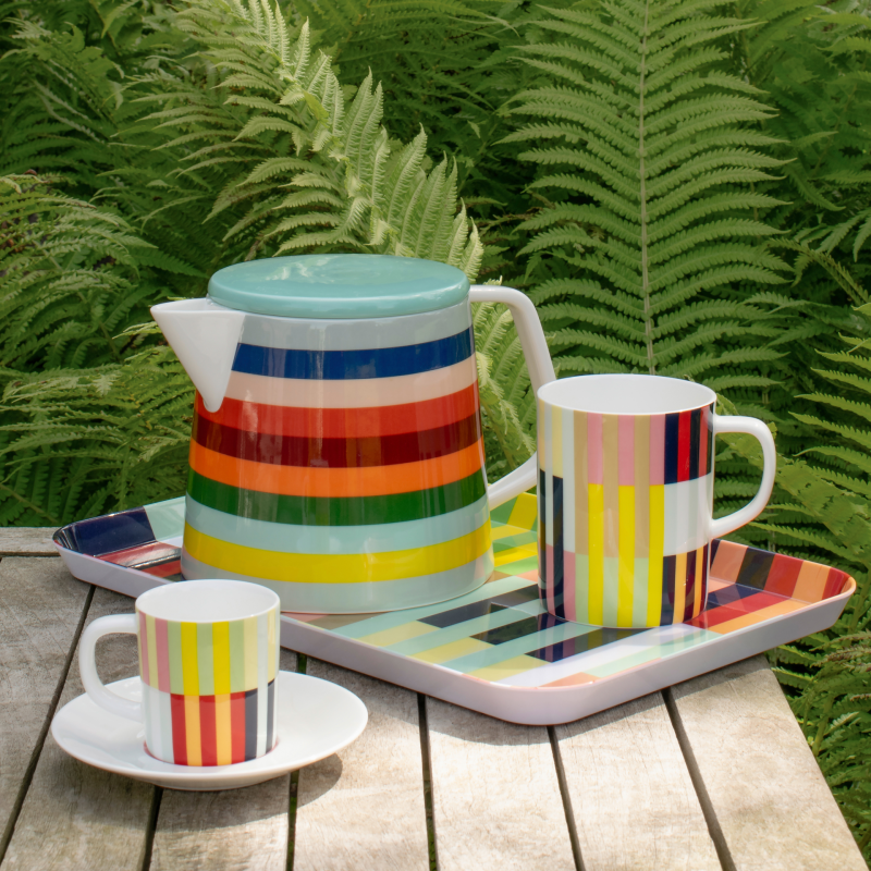 Taza de rayas de colores junto con un jarrón otra taza y bandeja del mismo modelo de la marca Remember.