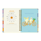 Páginas interiores de la agenda de Happimess 2026 Honrá tu poder, con checkpoint de junio y portadilla de julio con dos gatos en bicicleta