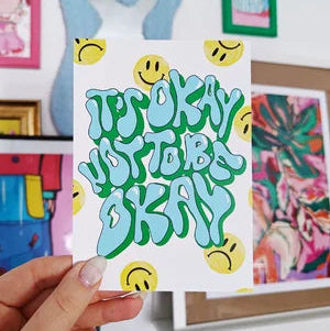 Postal con la frase It's ok not to be ok y caritas smiley contentas y tristes