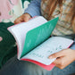 Chica hojeando el cuaderno Journal Sessions, para practicar la escritura escribiendo un diario con disparadores