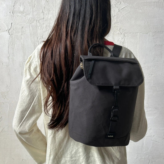 Mochila Kaut mini Arles Cemento de Lefrik en gris oscuro, llevada a la espalda para mostrar su tamaño compacto.