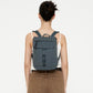 Vista trasera de modelo con la mini mochila Lefrik Kaut verde laurel puesta, mostrando el ajuste y las correas