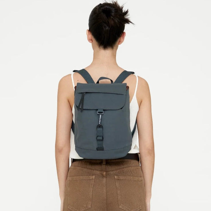 Vista trasera de modelo con la mini mochila Lefrik Kaut verde laurel puesta, mostrando el ajuste y las correas