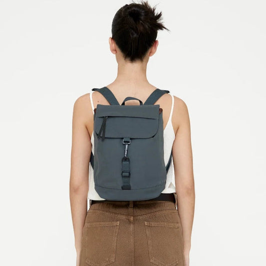 Vista trasera de modelo con la mini mochila Lefrik Kaut verde laurel puesta, mostrando el ajuste y las correas