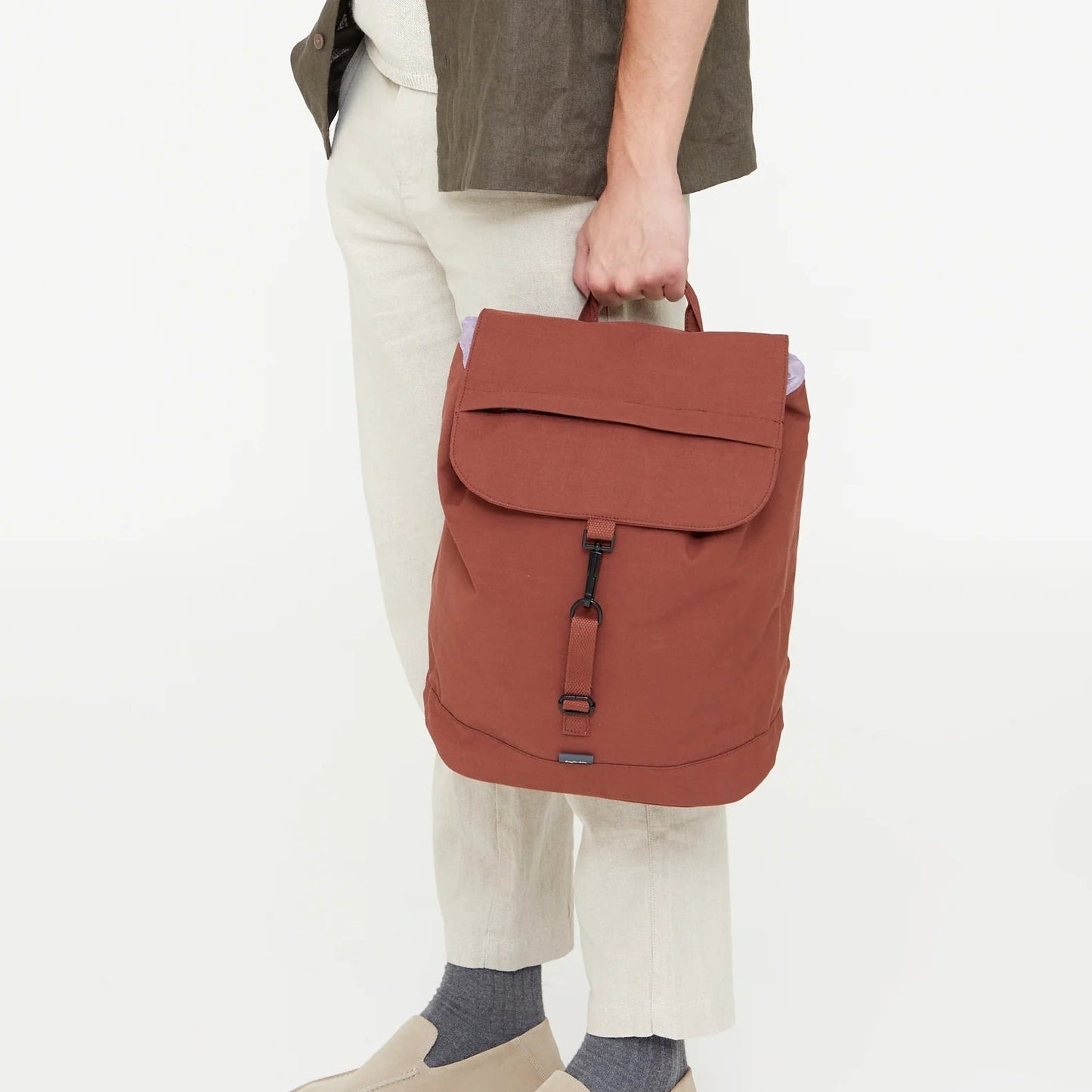 modelo con la mochila scout arles en color bronze cogida por el asa superior