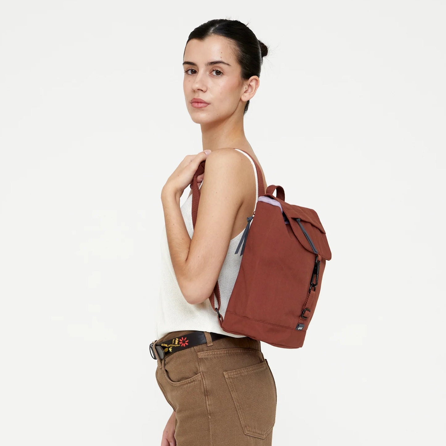 chica posando con la mochila scout mini arles de lefrik en color bronze teja rojizo, colocada sobre un hombro