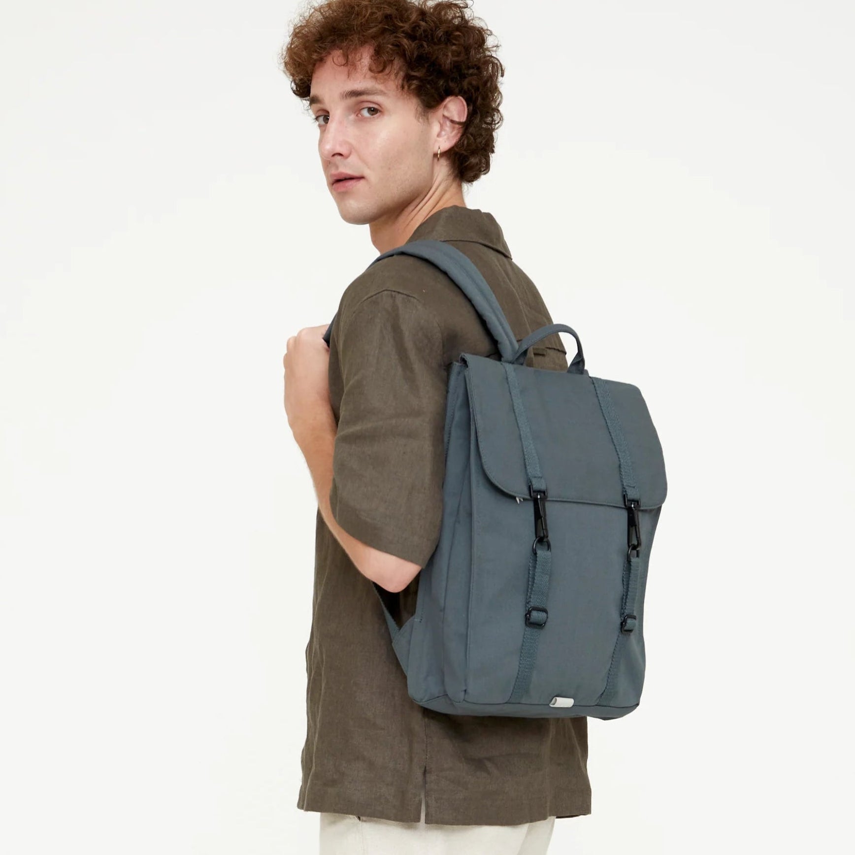 chico posando con la mochila de lefrik del modelo handy en color azul hoja de laurel sobre uno de los hombros