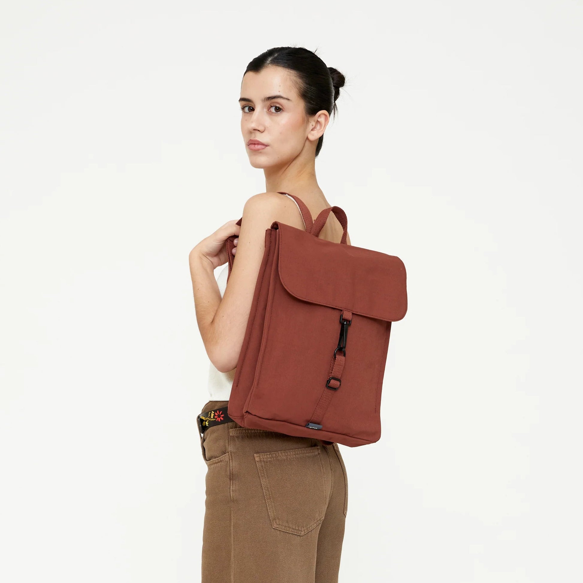modelo posando con la mochila handy mini de lefrik en color teja bronze puesta sobre un hombro