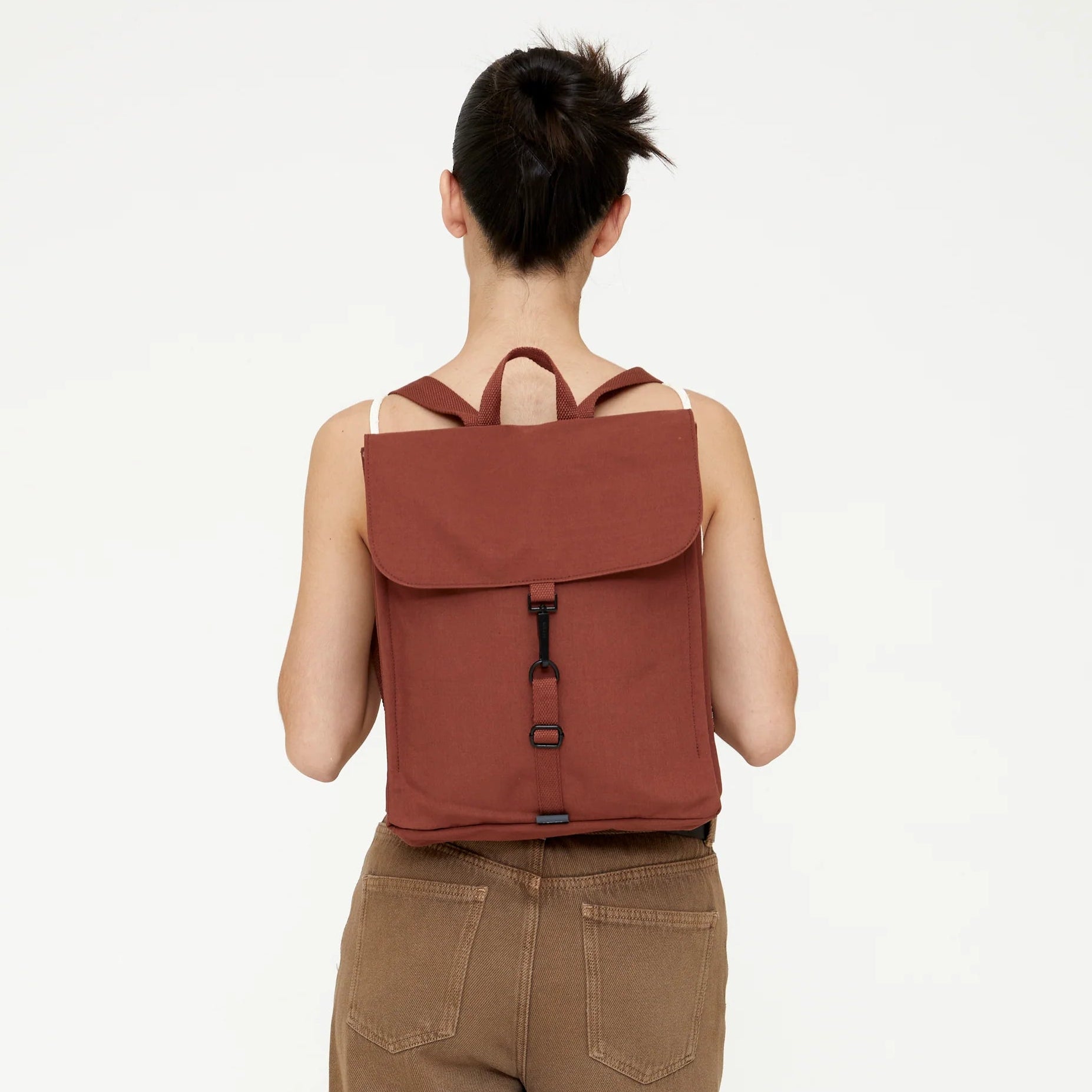 modelo de espaldas con la mochila de lefrik handy mini puesta, en color bronze