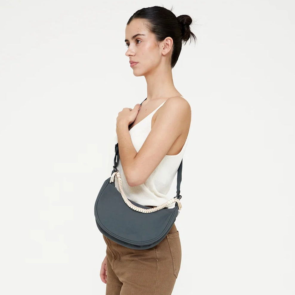 modelo de lado posando con el bolso lua de lefrik en color hoja de laurel llevandolo como una bandolera cruzada