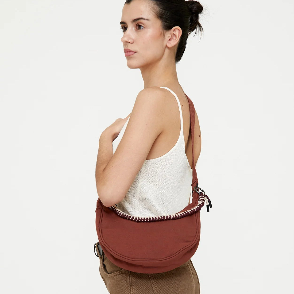 modelo de lado llevando el bolso lua en color bronze como bandolera cruzada