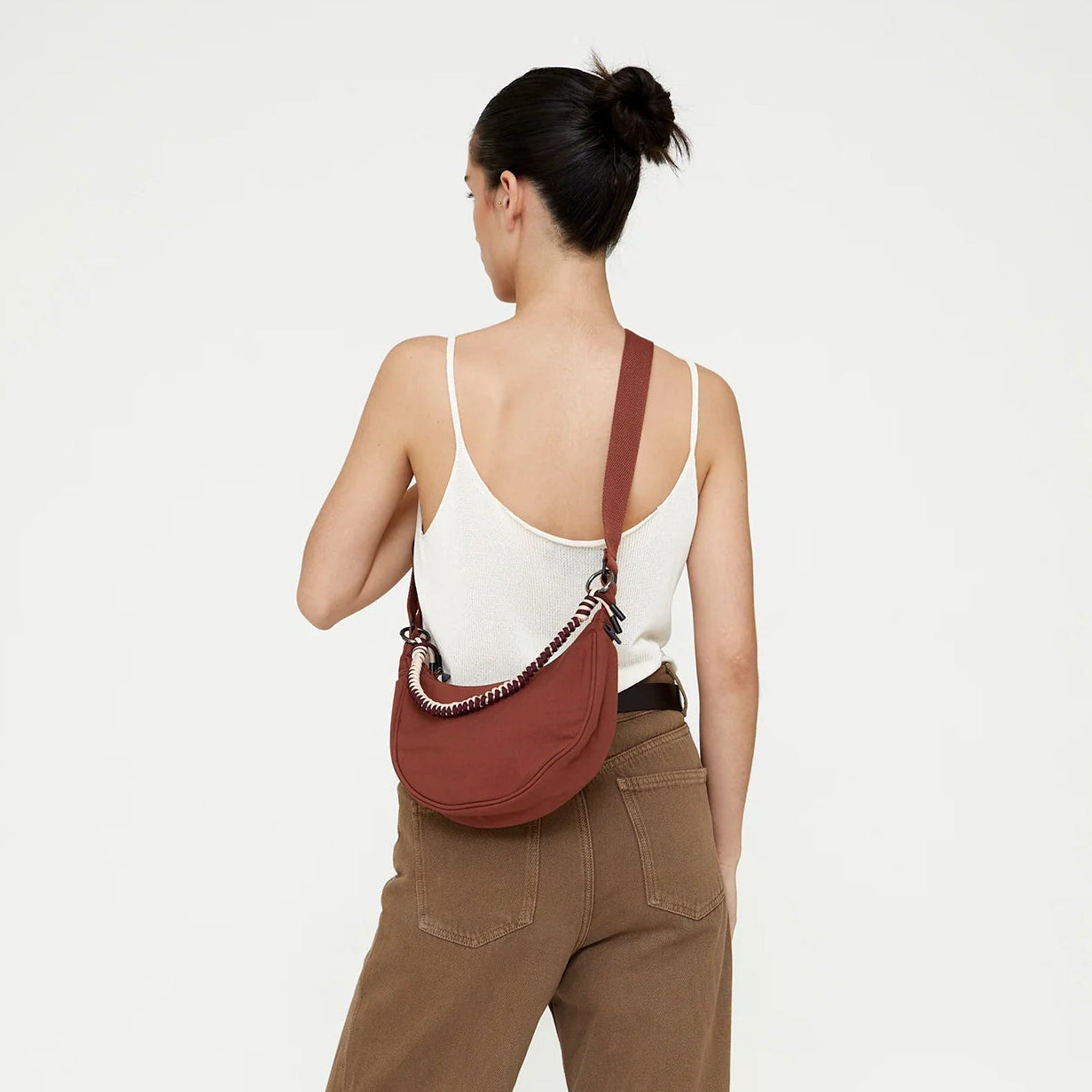 modelo de espaldas llevando un bolso lua de lefrik en color marrón bronze con correa trenzada en color crema