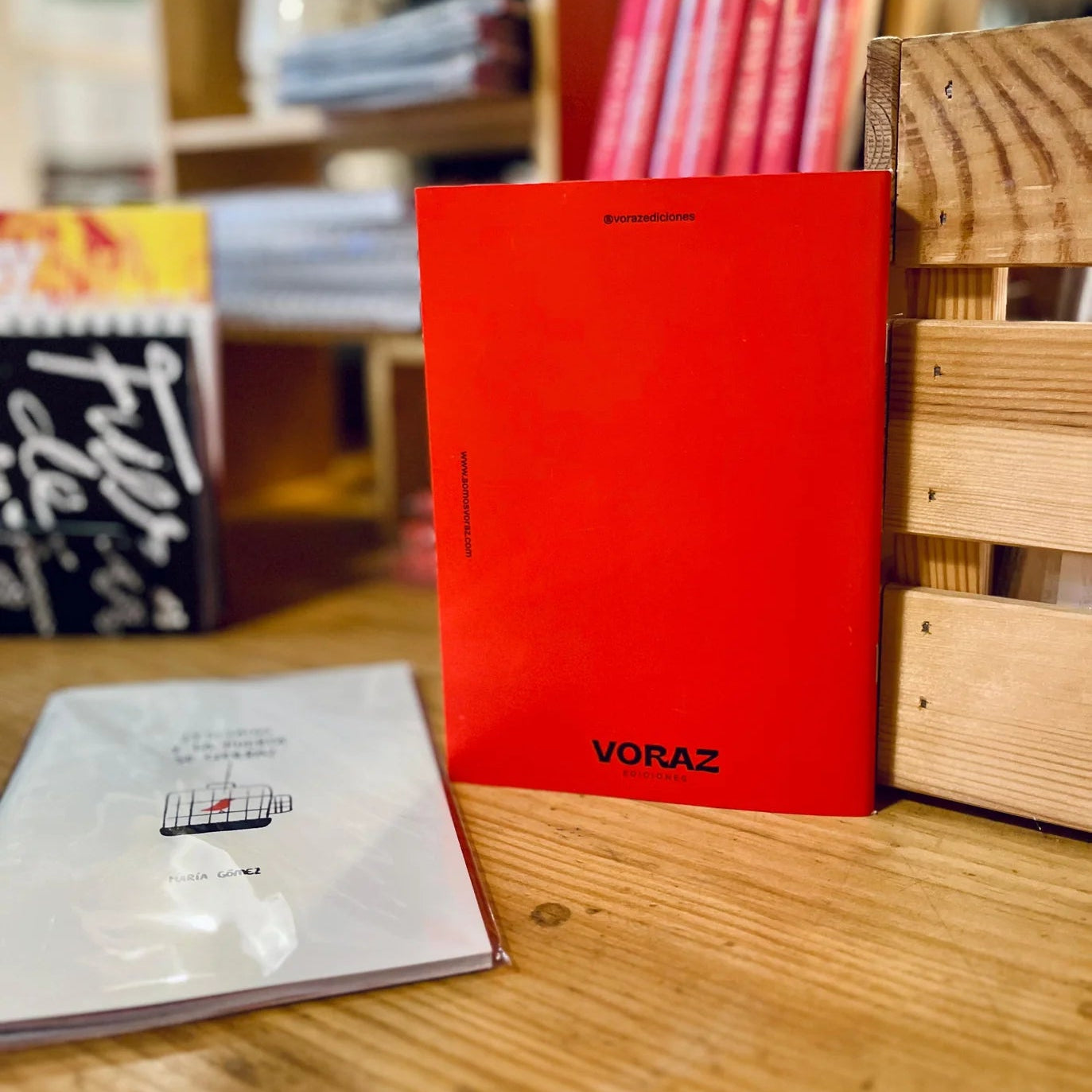 libreta con grapas de la marca voraz con un dibujo de un pájaro de color rojo en una jaula y con el texto ¿y si salgo y la puerta se cierra? y parte de atrás en color rojo