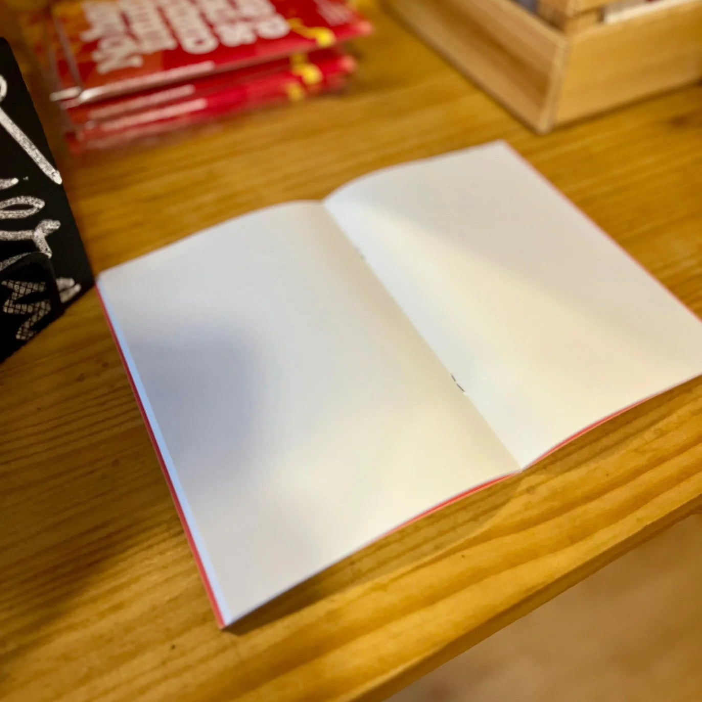 libreta con grapas de la marca voraz con un dibujo de un pájaro de color rojo en una jaula y con el texto ¿y si salgo y la puerta se cierra? abierta totalmente con páginas blancas en el interior