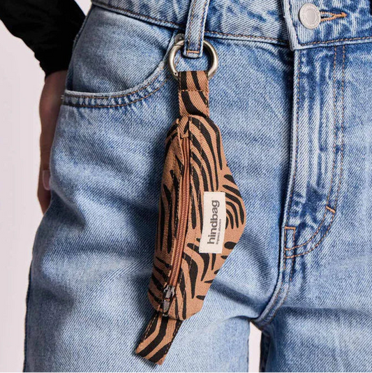 Llavero cebra color canela con forma de plátano enganchado a unos vaqueros. 