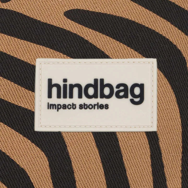 EL logo de Hindbag sobre una tela estampada cebra color canela de fondo. 