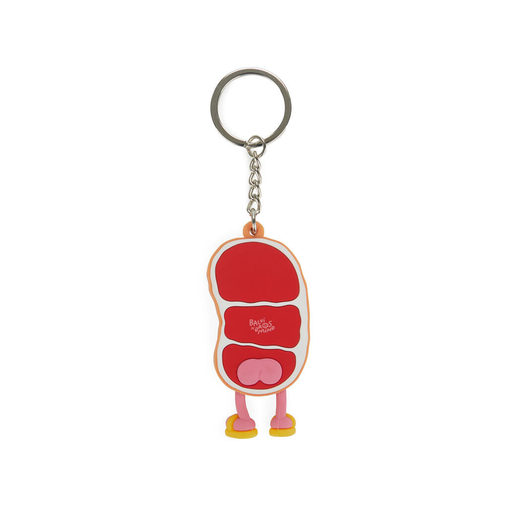 Parte trasera de llavero de filete de carne de ternera Gyu Sensei, roja con detalles blancos que imitan la grasa de la propia carne, tiene una cara sonriente, piernas rosas y chanclas amarillas, tiene un detalle en rosa de su trasero, sobre fondo blanco. 
