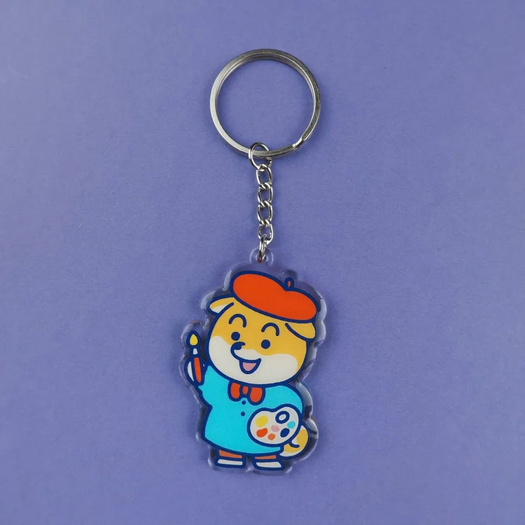 Llavero de acrílico reciclado con forma de perro shiba con boina de artista, pincel y paleta de acuarelas