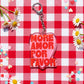 Llavero More Amor de Laura Ortiz, con corazón rosa y letras rojas «More amor por favor», sobre mantel de cuadros con margaritas.

