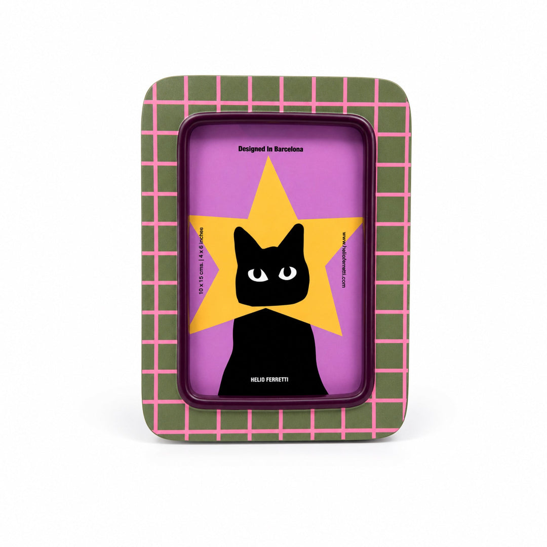 Marco a cuadros verdes y rosas con una imagen de un gato negro con la cabeza metida en una estrella amarilla sobre fondo morado