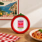 «Marco de fotos Tomate de Helio Ferretti, rojo con hojas verdes, sobre una mesa junto a un plato de pasta.»
