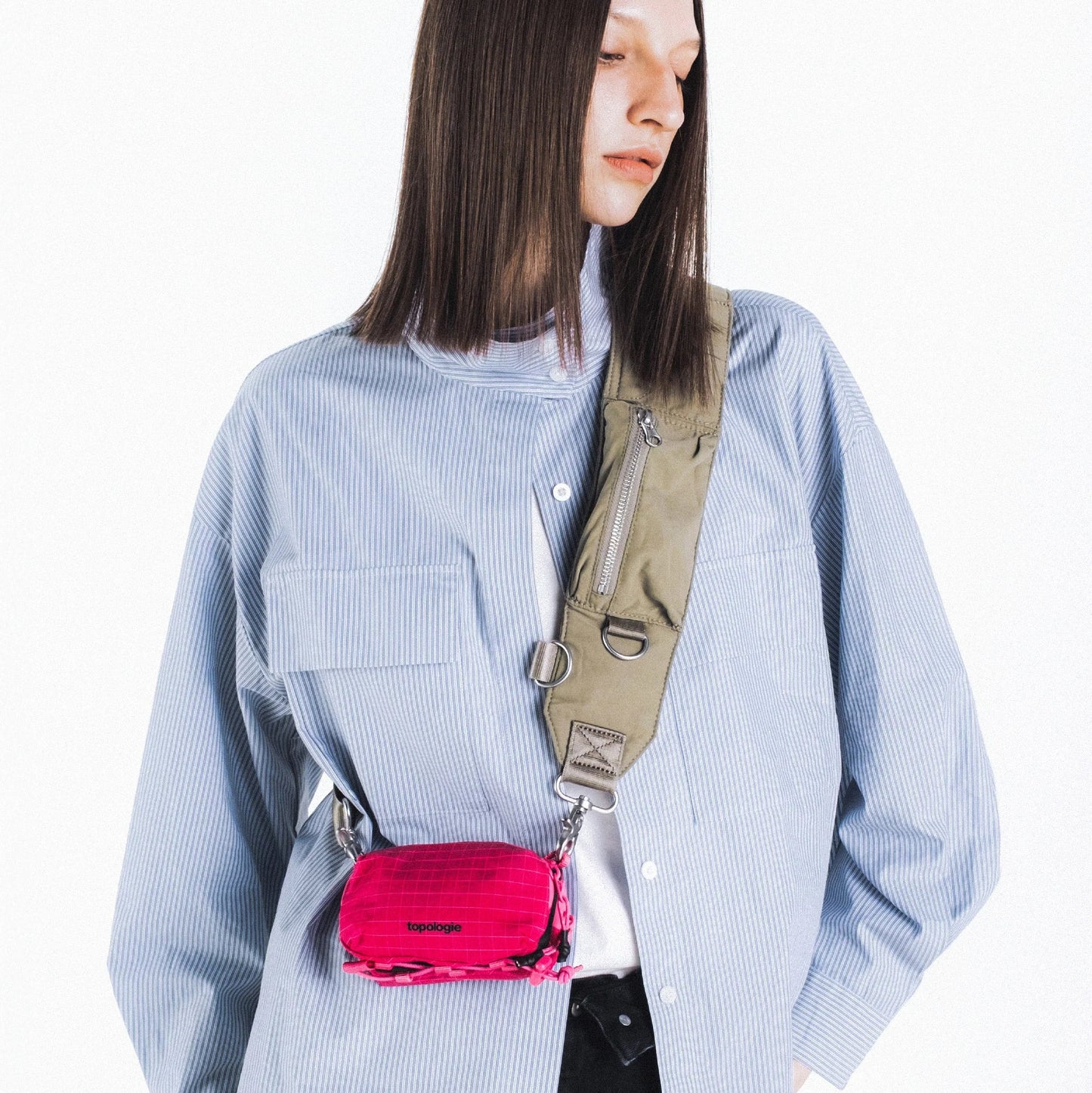Chica con el bolso Mini Bottle Sacoche de Topologie en color fucsia colgado de una correa de hombro