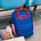 Mochila azul marino y rojo con la palabra "ciao" en el suelo de una sala de espera