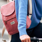 Mujer en bicicleta con un jersey azul y la mochila pequeña color rosa de algodón orgánico de la marca francesa Hindbag