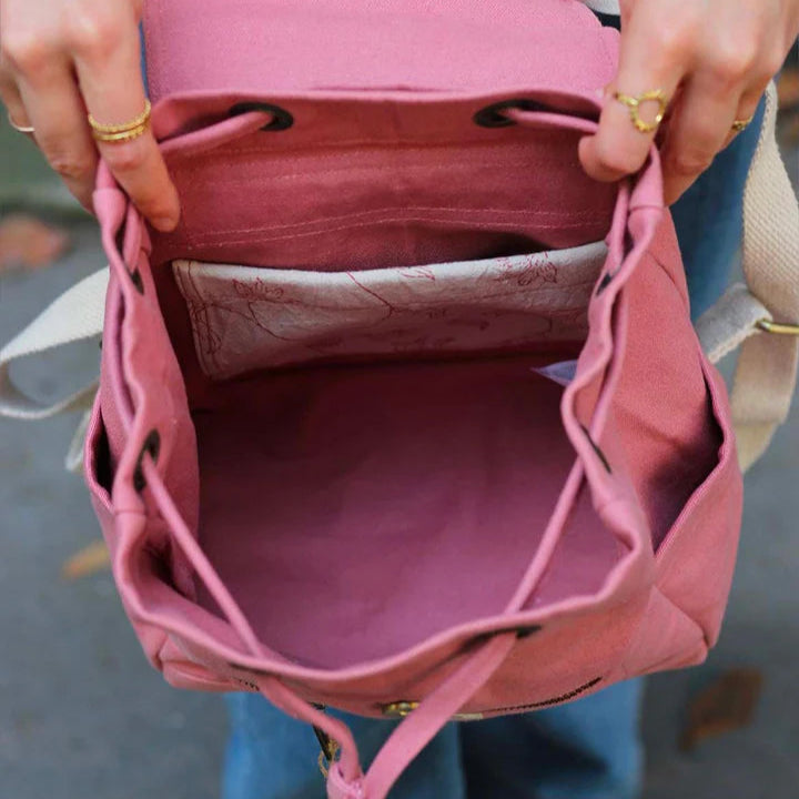 Mujer enseñando el interior de la mochila pequeña color rosa de algodón orgánico de la marca francesa Hindbag