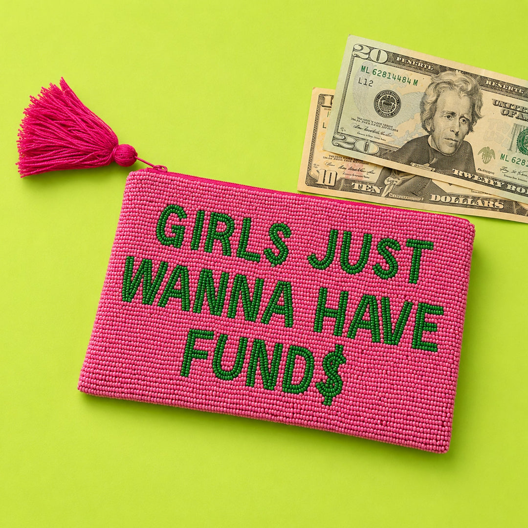 Monedero de cuentas de cristal rosas con cremallera y borla y el mensaje GIRLS JUST WANNA HAVE FUNDS con un símbolo de dólar en la S junto a unos billetes de dólar