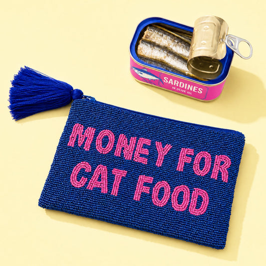 Monedero grande hecho de cuentas azul marino con borla en la cremallera y el mensaje MONEY FOR CAT FOOD en cuentas rosas al lado de una lata de sardinas