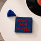 Monedero azul marino con cuentas y el mensaje MONEY FOR MUSIC en rojo puesto en una mesa con un disco de vinilo al lado