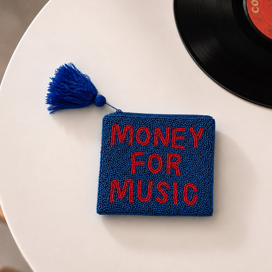 Monedero azul marino con cuentas y el mensaje MONEY FOR MUSIC en rojo puesto en una mesa con un disco de vinilo al lado