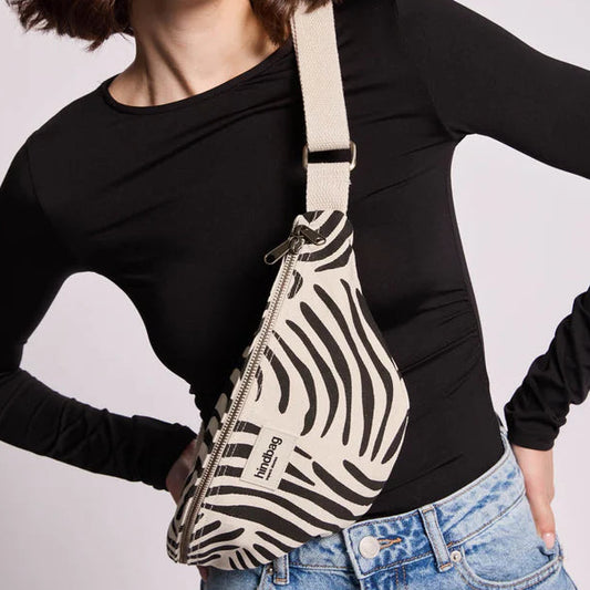 Riñonera del modelo Olivia con estampado cebra y color blanco crudo de fondo, puesto sobre una persona. 