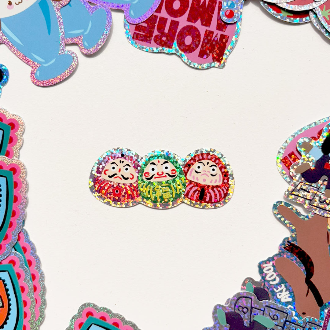Pegatina con forma de tres amuletos japoneses daruma con los dos ojos ya pintados 