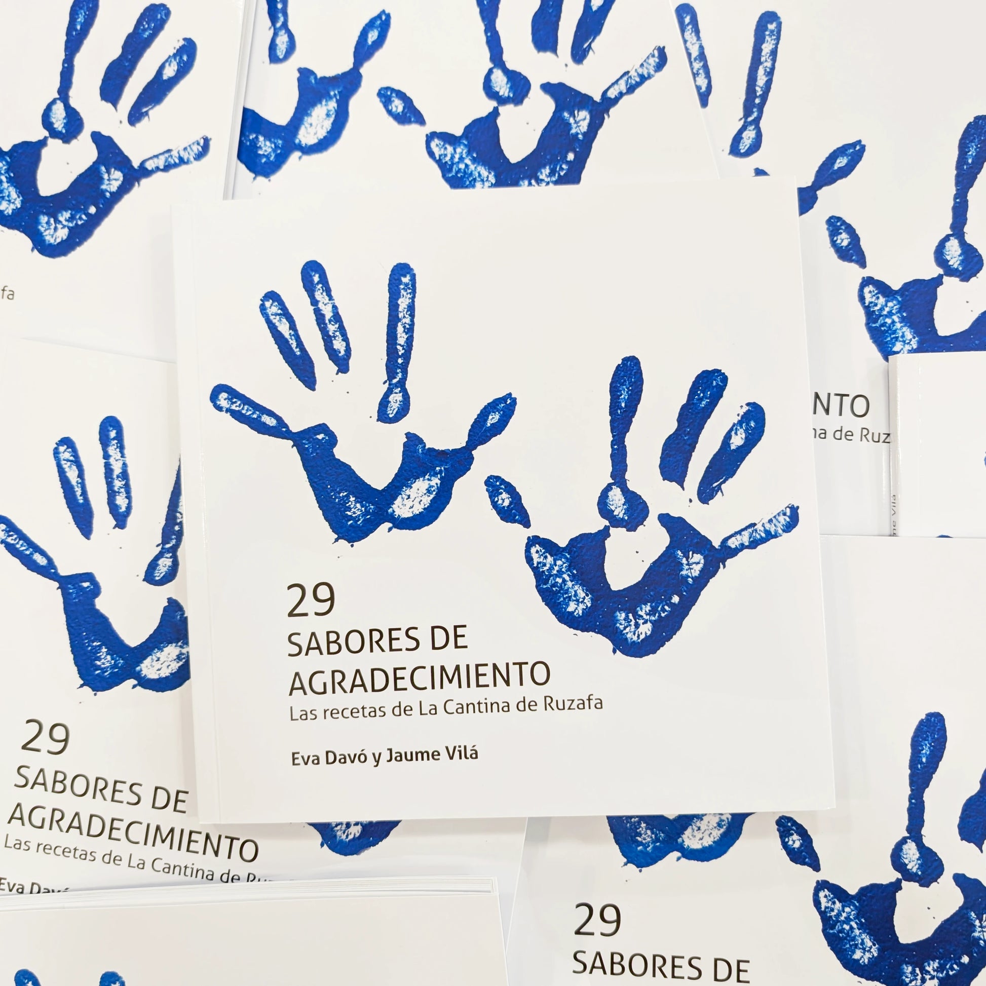portada del libro de cocina 29 sabores de agradecimiento. las recetas de la cantina de ruzafa, de Eva Davó y Jaume Vilá. Con el fondo blanco y una silueta de unas manos manchadas en color azul