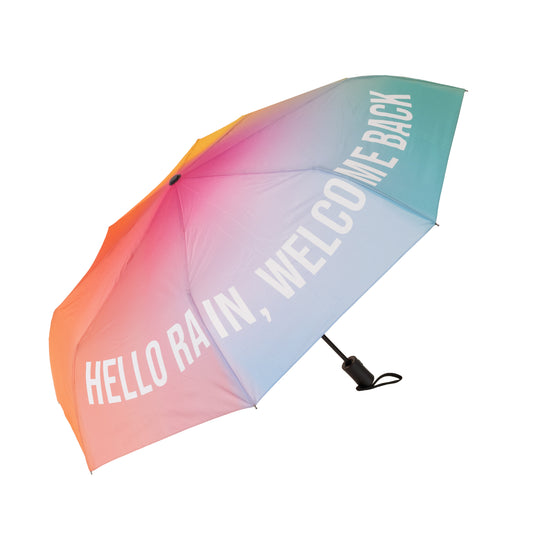 Paraguas plegable con esqueleto negro y estampado degradado de colores con el mensaje Hello rain, welcome back en letras mayúsculas blancas