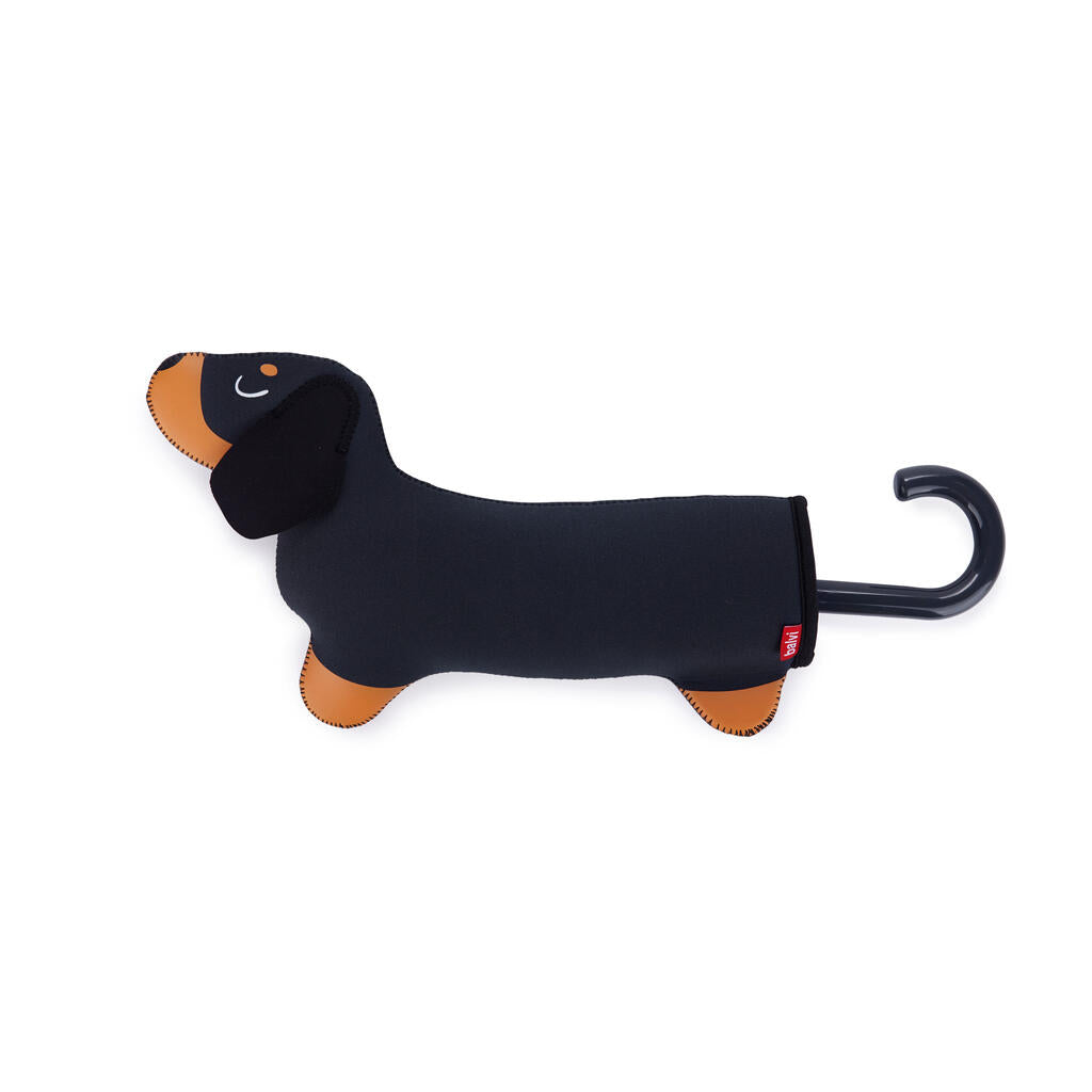 Paraguas guardado en una funda con forma de perro salchicha negro y marrón, con el mango curvo a modo de cola.