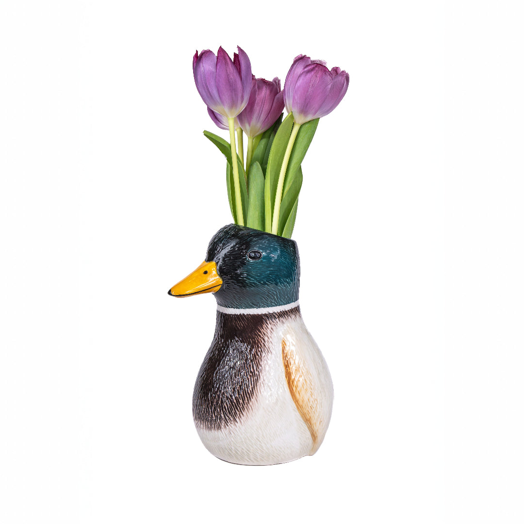 Florero en forma de pato de collar con tulipaness violetas dentro sobre fondo blanco. 