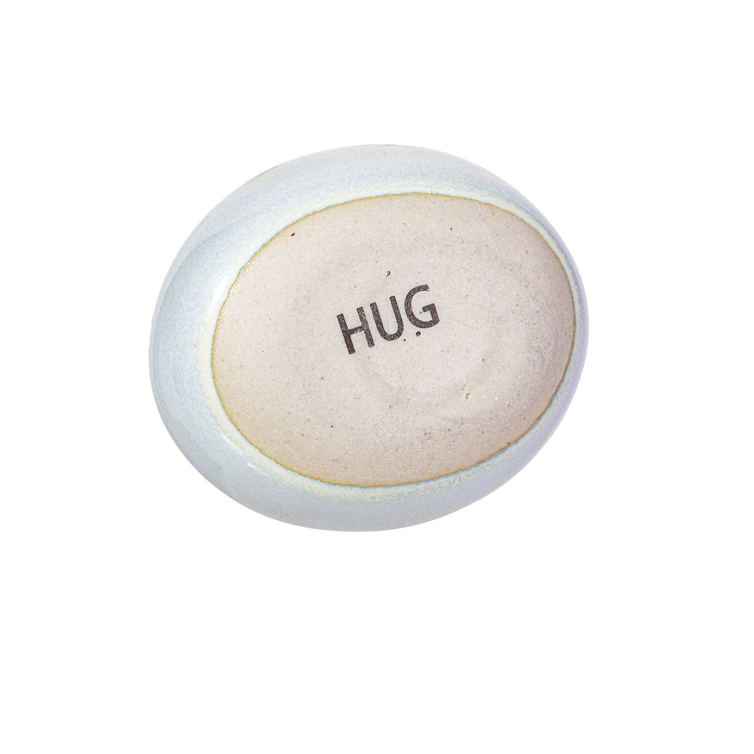 Parte de abajo de la piedrecita, con el letrero "HUG" sobre fondo blanco. 